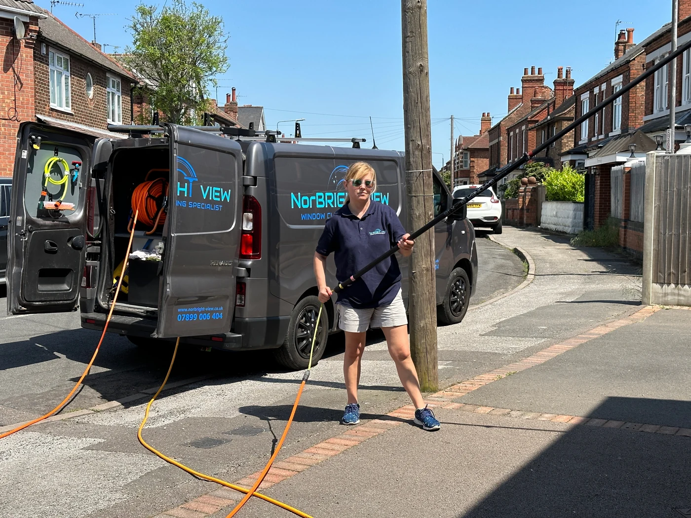 NorBRIGHT View team member holding a water-fed pole beside the company van