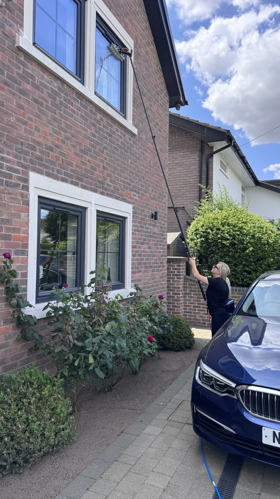 NorBRIGHT View team member cleaning an upstairs window with a water-fed pole